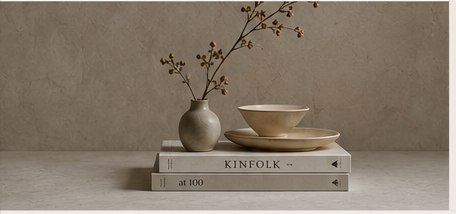 Stoneware vessels and a vase of branches arranged on interior design books